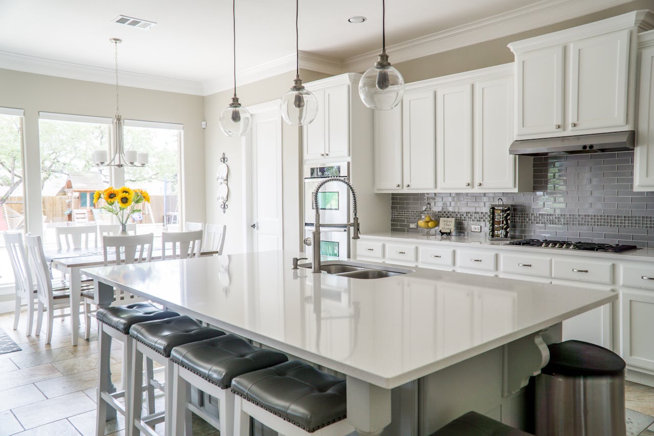 about-us Spacious modern kitchen with white cabinets and island in natural light.